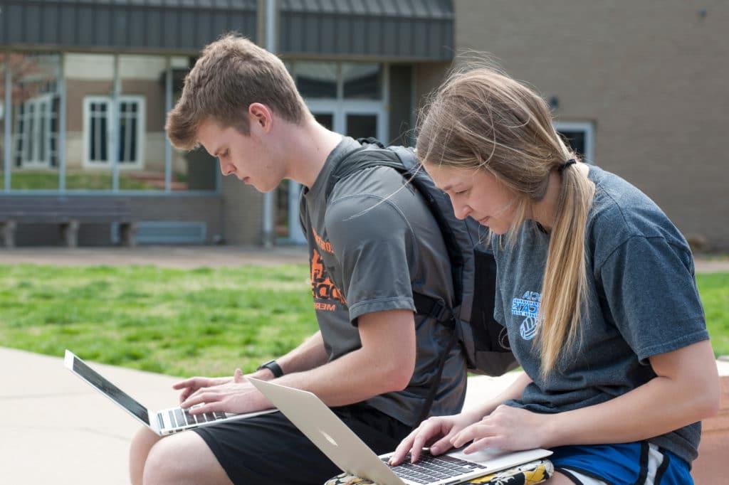两个学生在院子里用电脑做作业